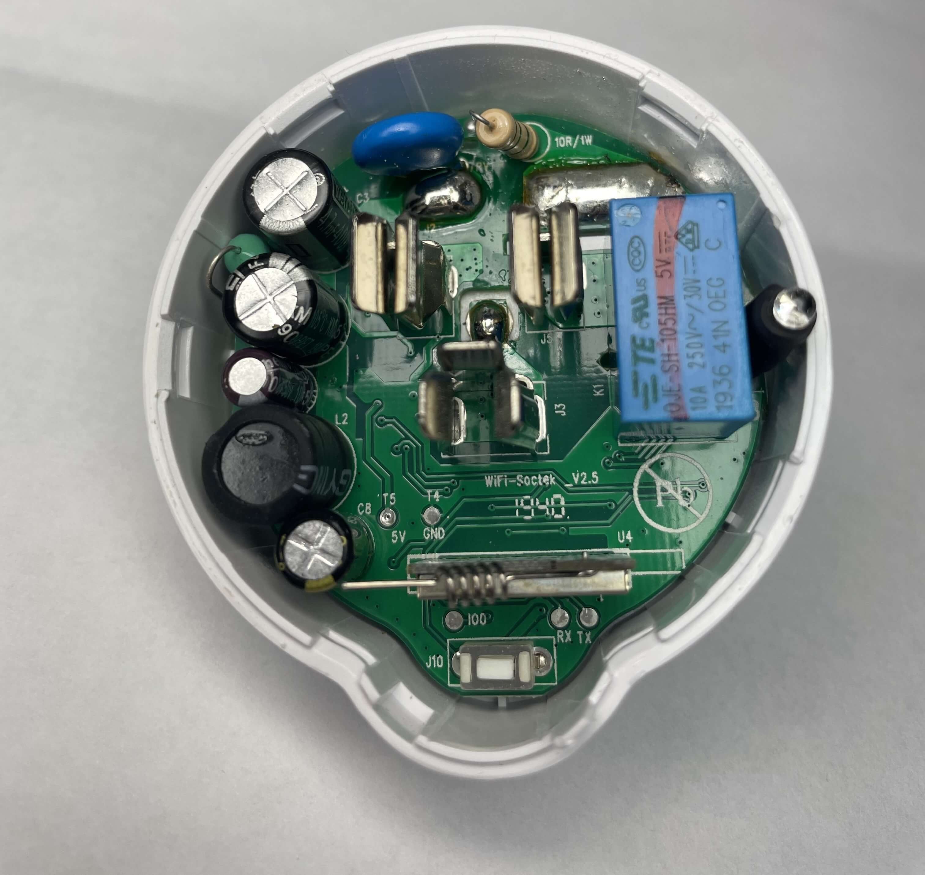 A top-down view of the Etekcity Voltson ESW01-USA-R6P's PCB. At the bottom of the PCB, there is an AI-Thinker ESP 01E module identifiable by its spring antenna. Below the ESP module, there are three test pads labeled, from left to right, as IO0, RX, and TX. Above and to the left of the ESP module, there are two test pads labeled, from left to right, as T5/5V and T4/GND.